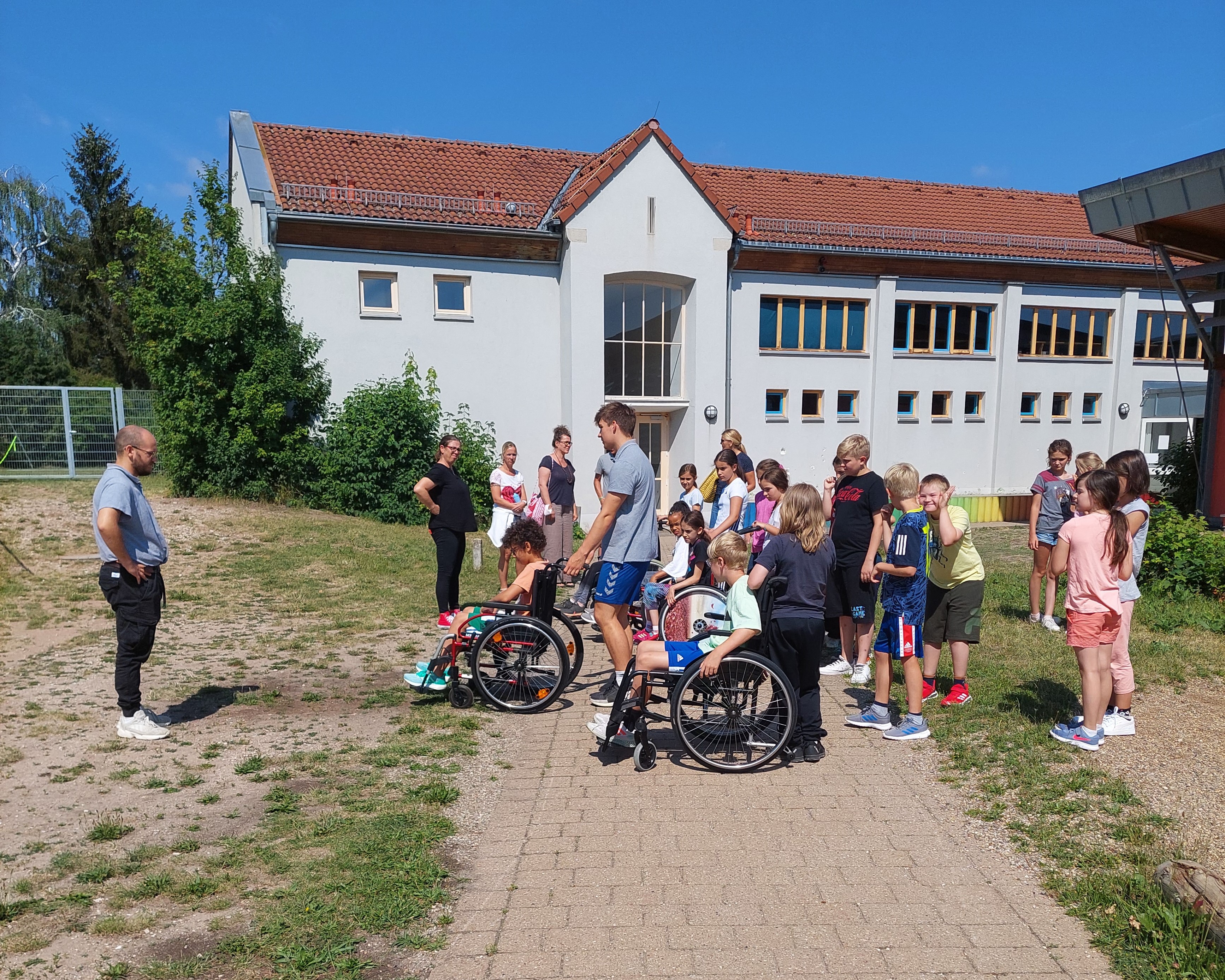 Schulklasse mit Trainer und Rollstühlen im Freien