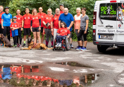 Gruppenbild der Läufer mit Hunden, Rollstuhl und dem goolkids-Bus