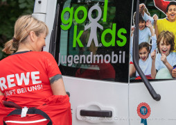 Ernährungsexpertin Ines mit REWE-Werbung in Pose beim goolkids-Bus